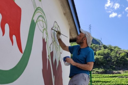 Lo street artist DEM lavora ad un murales con gli studenti